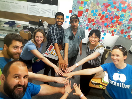 100In1Day participants putting their hands together in a circle.
