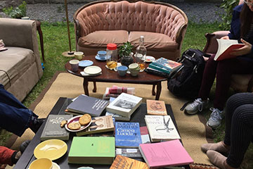 People sit around a table reading books in a park.