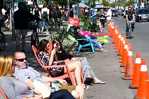 People relaxing in chairs on Queen St W.